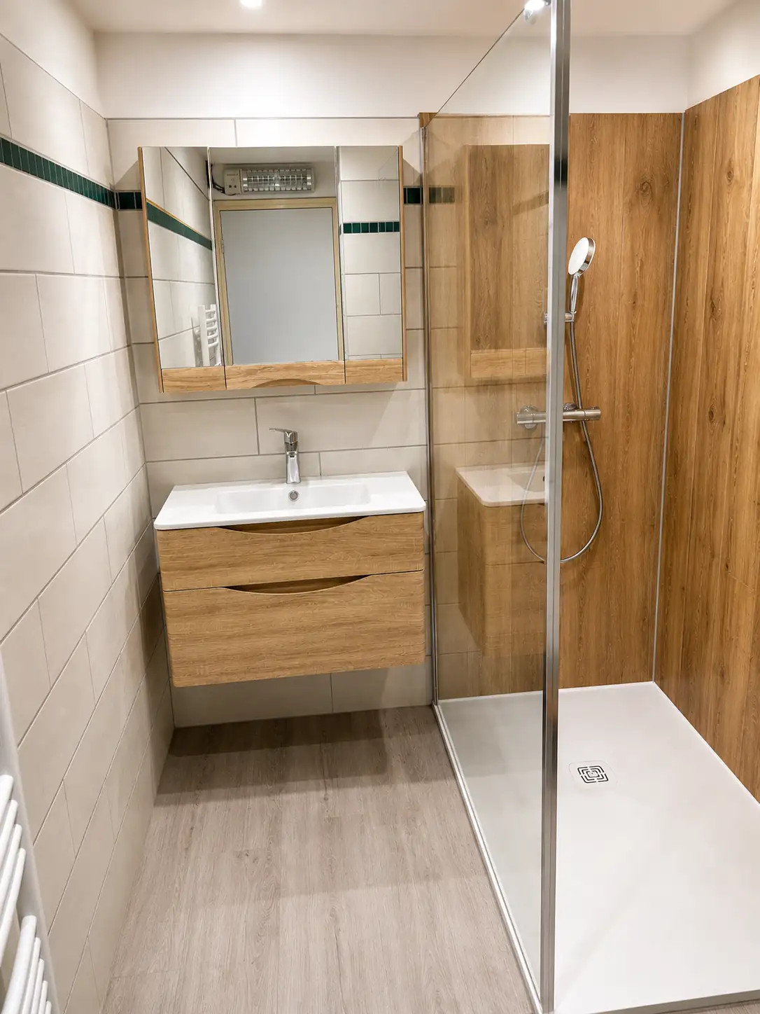 Salle d'eau rénovée par Erwan Pronost : meuble vasque suspendu, armoire de toilette à miroirs et sol effet bois