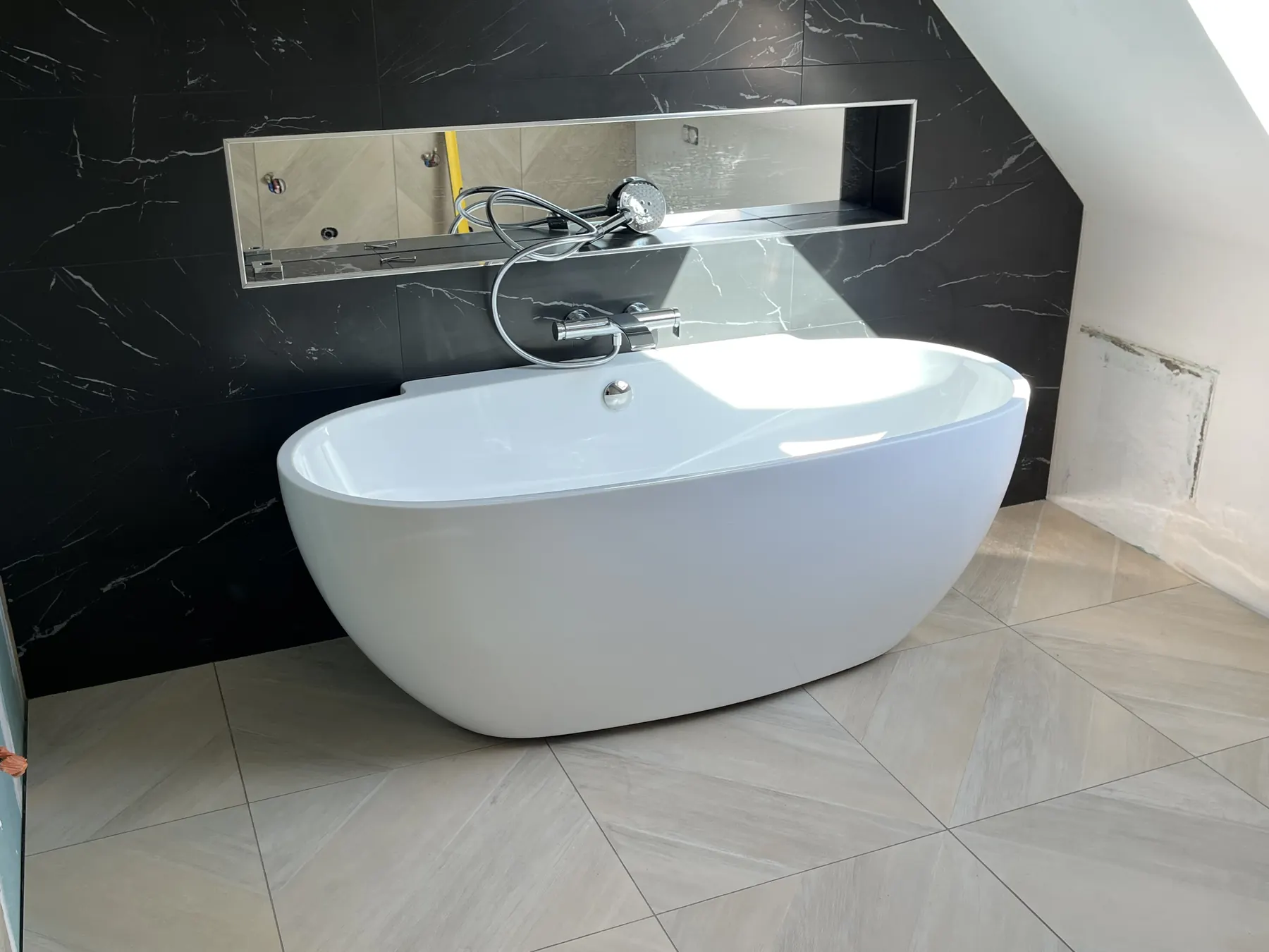 Salle de bain rénovée par Erwan Pronost : baignoire îlot et faïence marbre noir