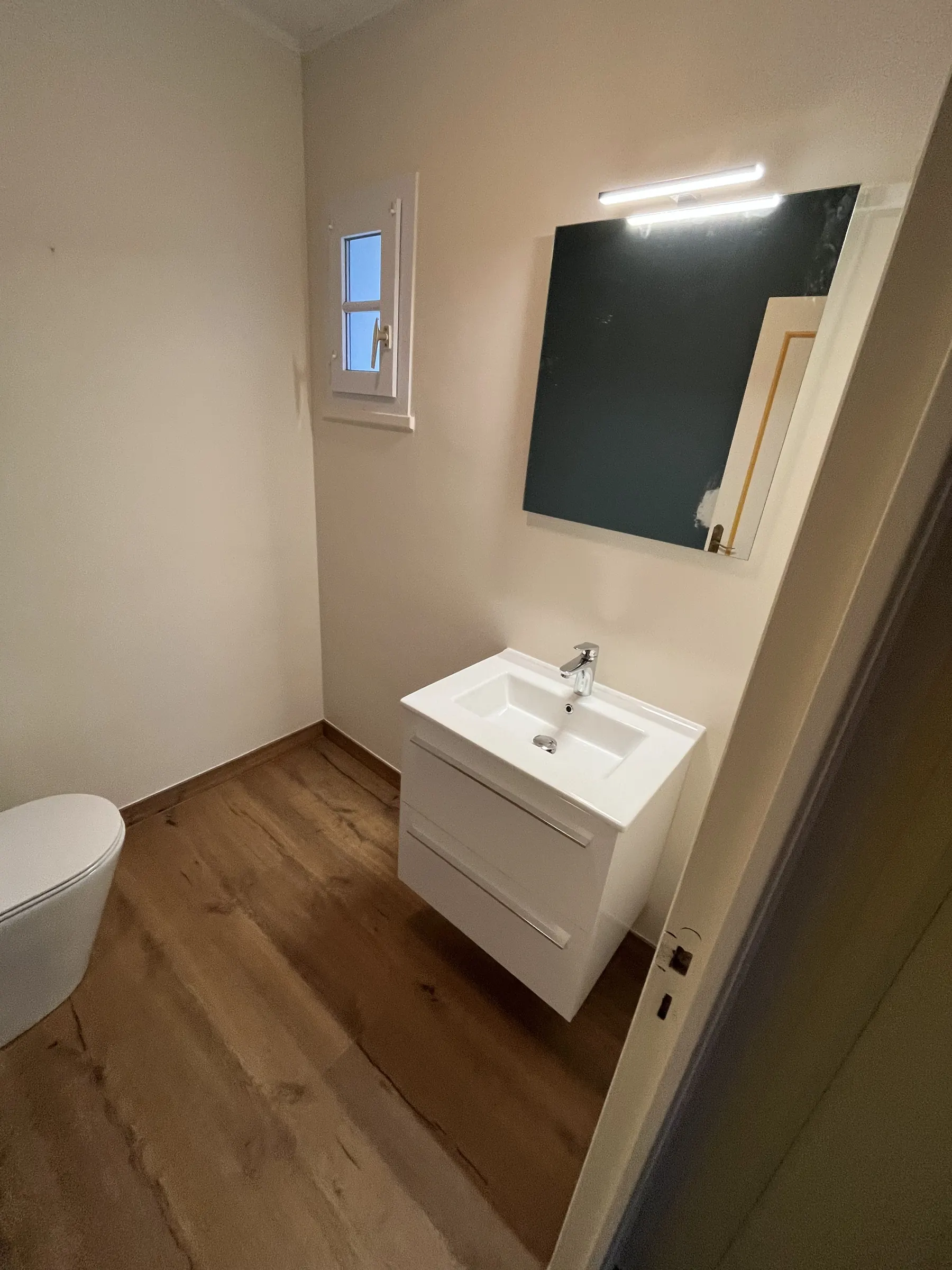 Meuble vasque blanc et WC dans une pièce d'eau lumineuse