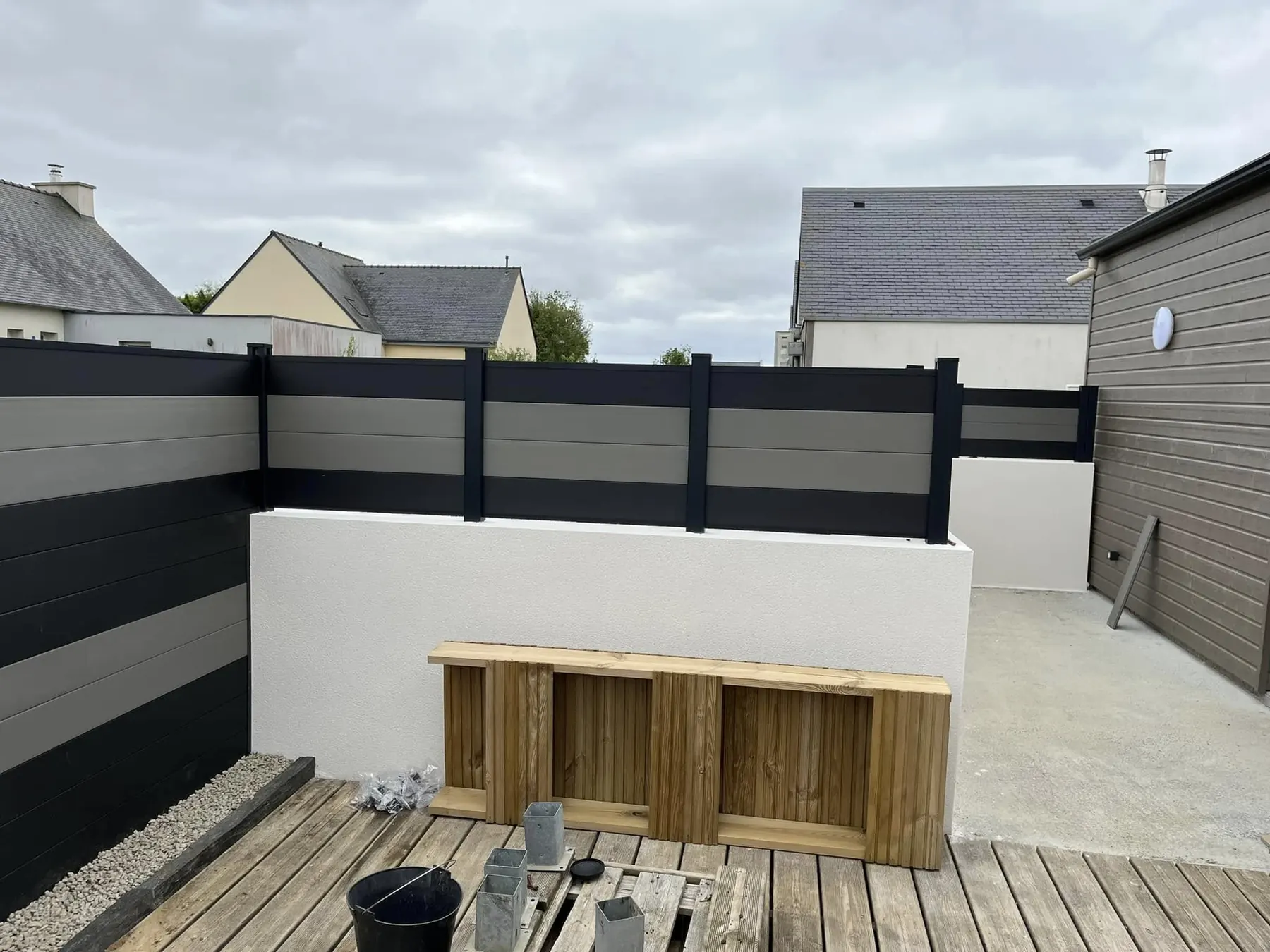 Clôture composite anthracite et terrasse bois en cours de finition