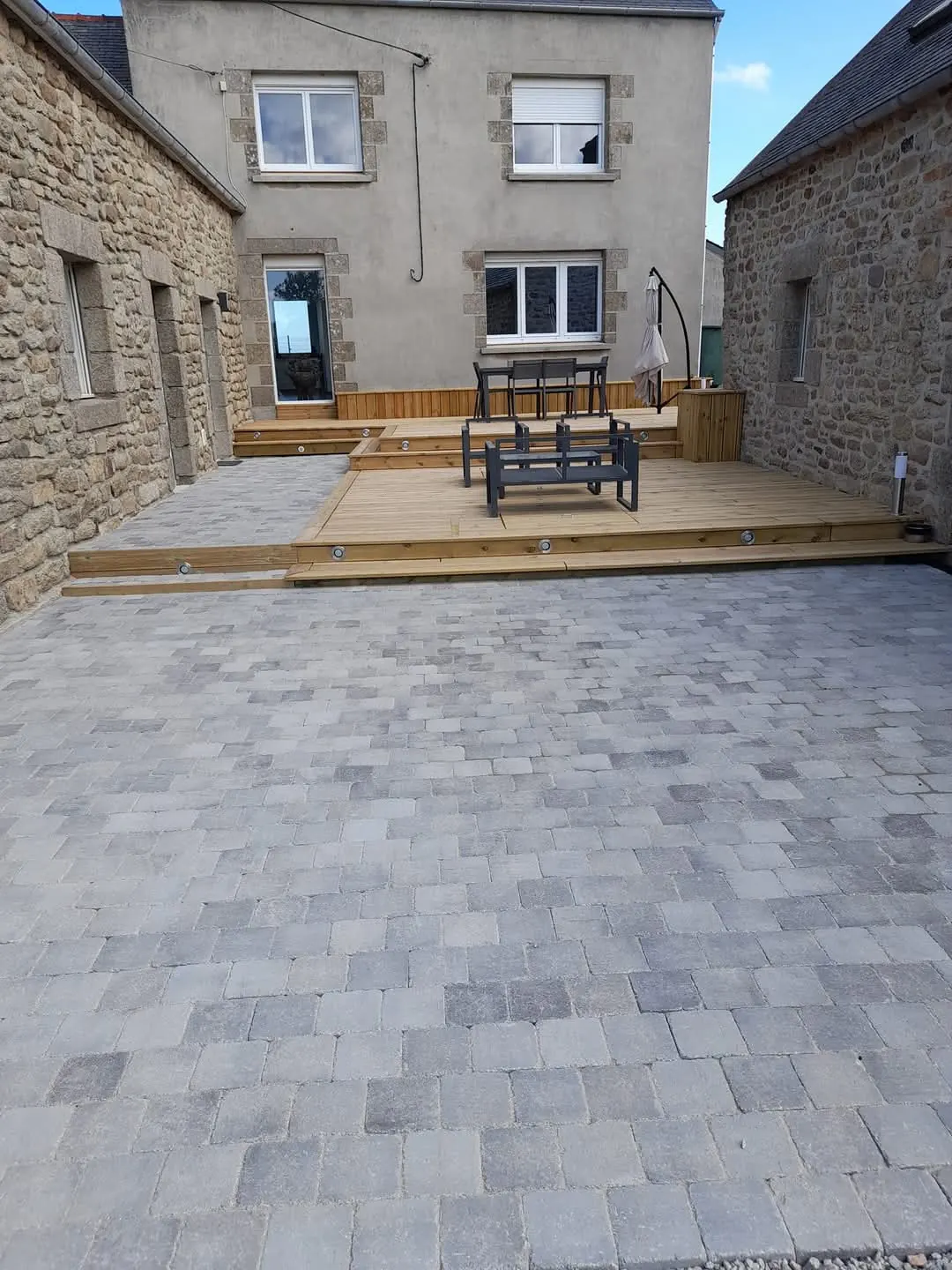 Terrasse bois et pavage réalisés devant une maison en pierre bretonne