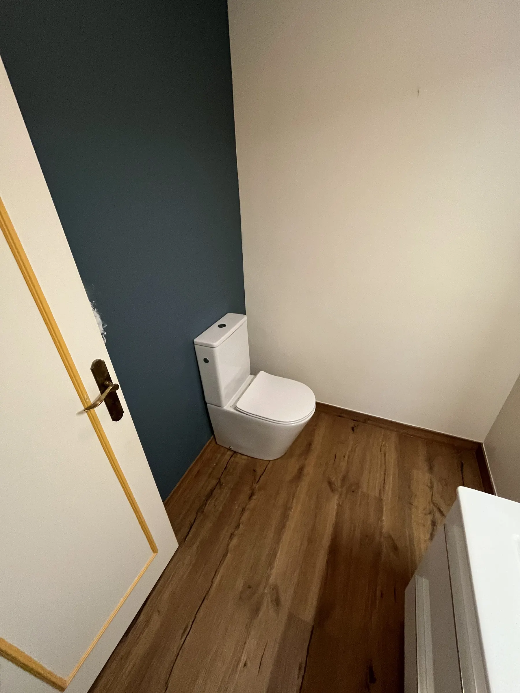 WC rénové avec mur bleu canard et sol stratifié bois