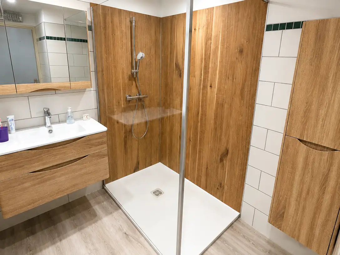 Douche à l'italienne avec receveur extra-plat, paroi vitrée et panneaux muraux effet chêne